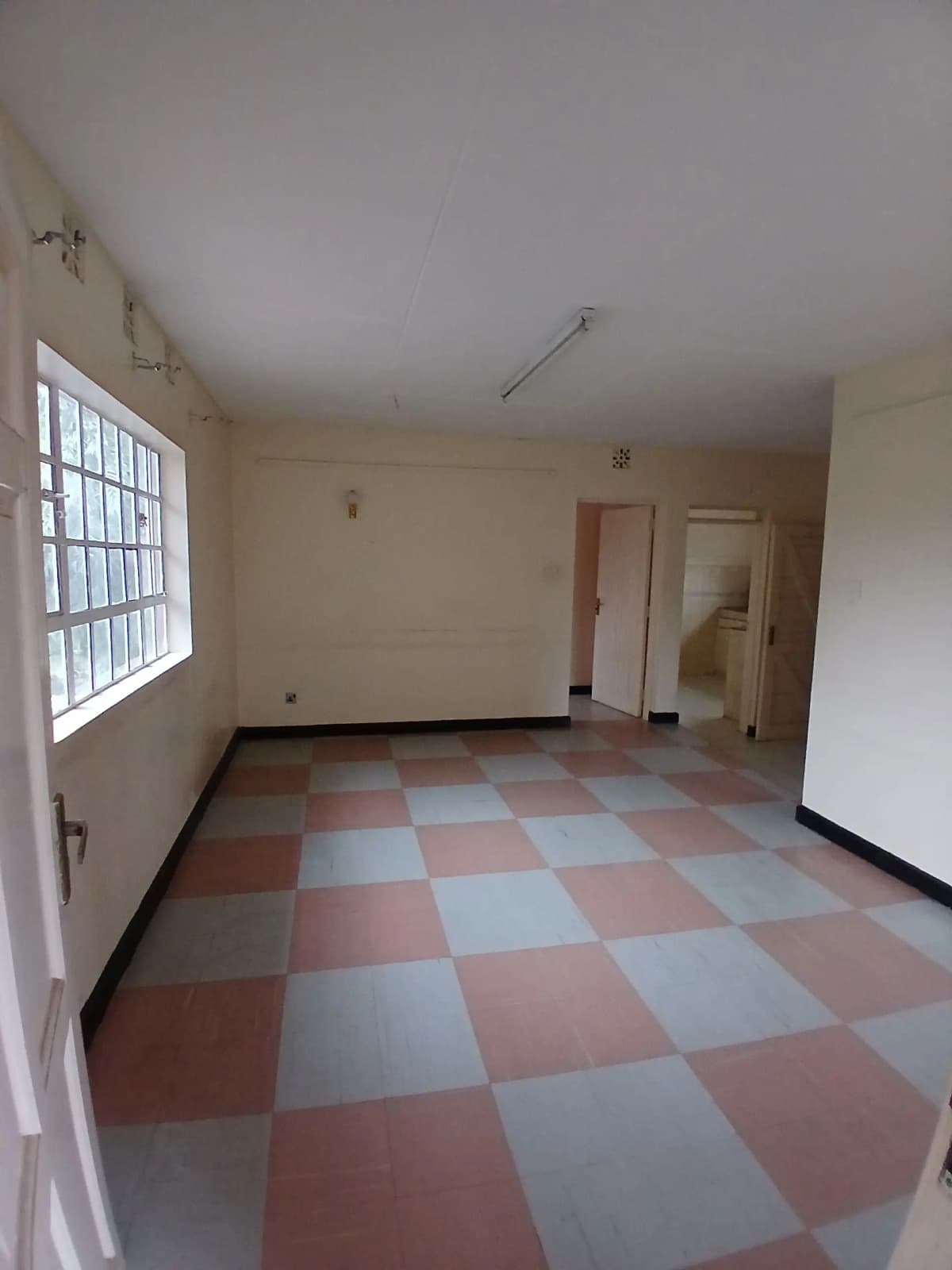 Empty living room with checkerboard floor and barred window