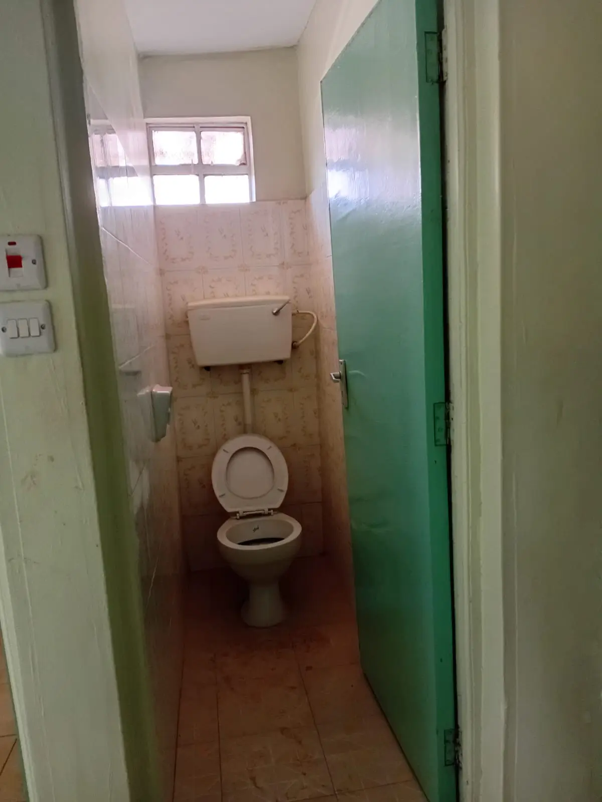 Narrow bathroom with toilet, sink, and small window