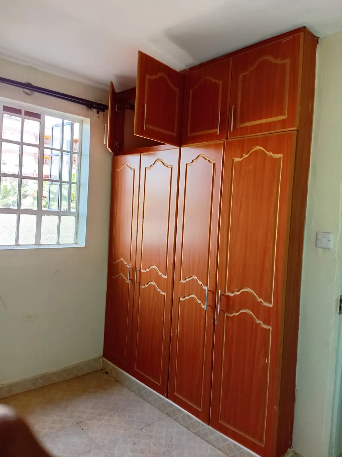 Bedroom with large wooden wardrobe and natural window light