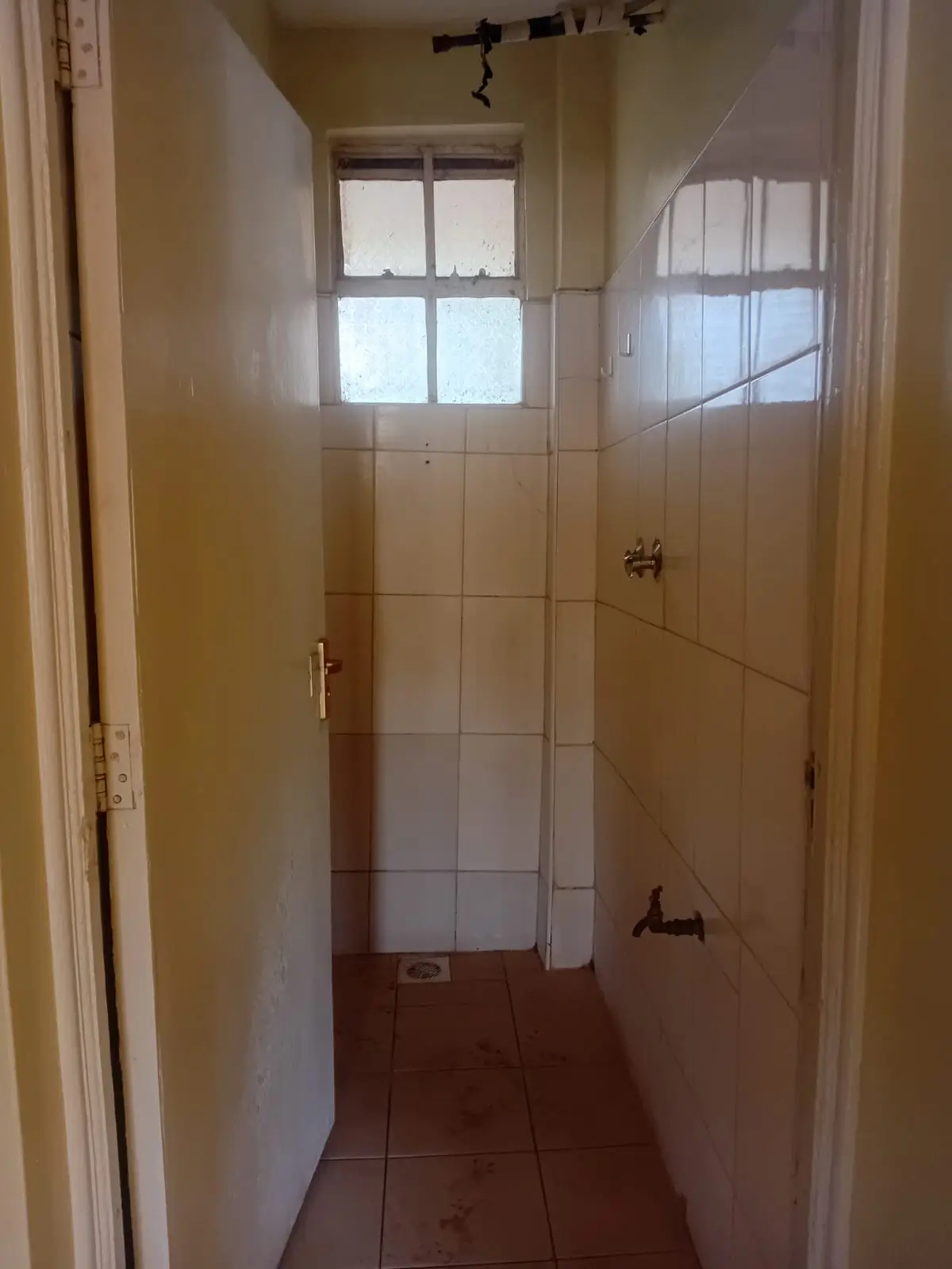 Narrow bathroom with tiled walls and window light