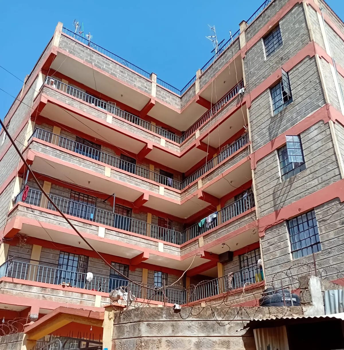 Multi-story residential building with red balconies and stone facade