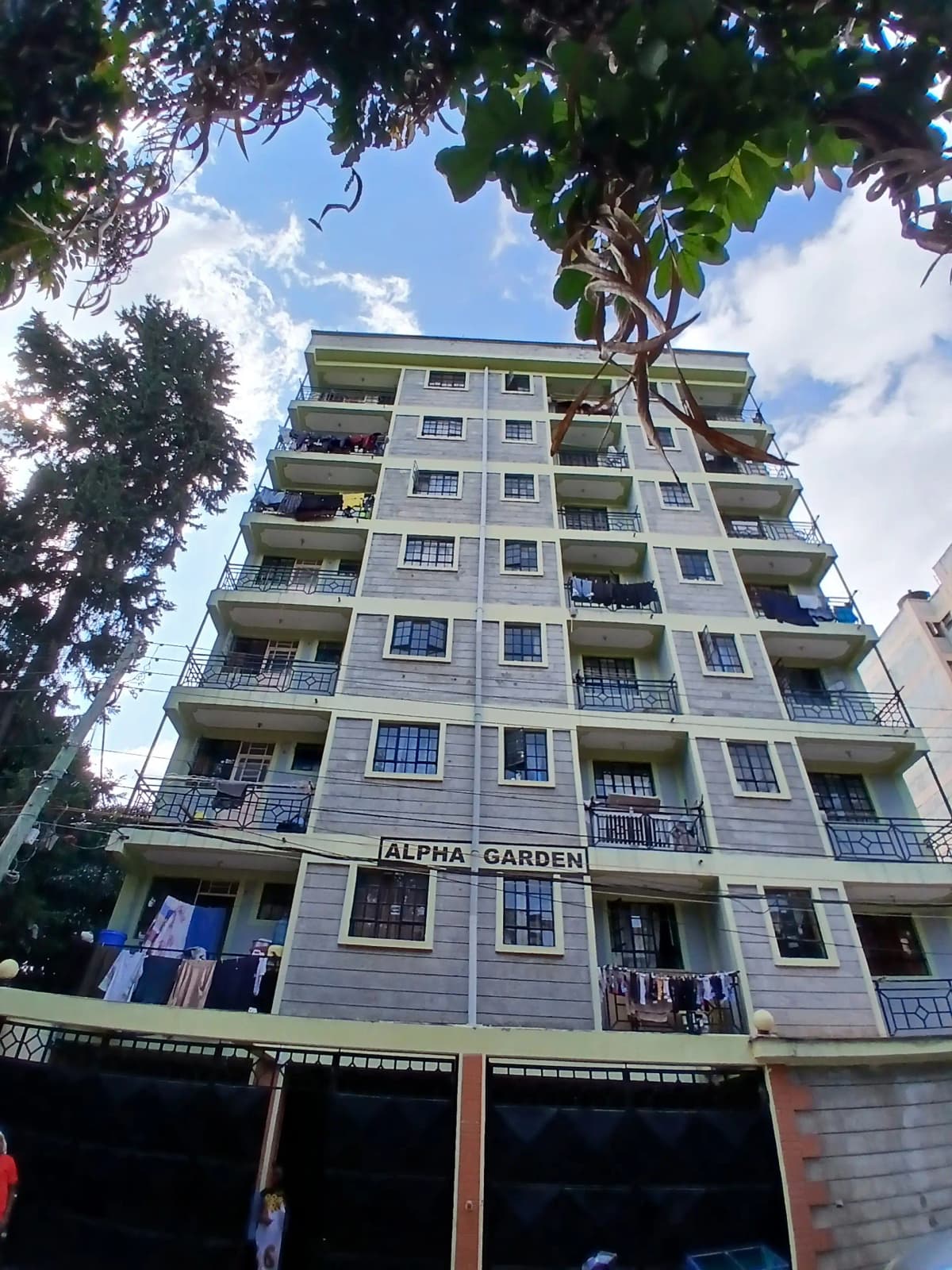 Modern multi-story residential building with balconies and ground-floor parking