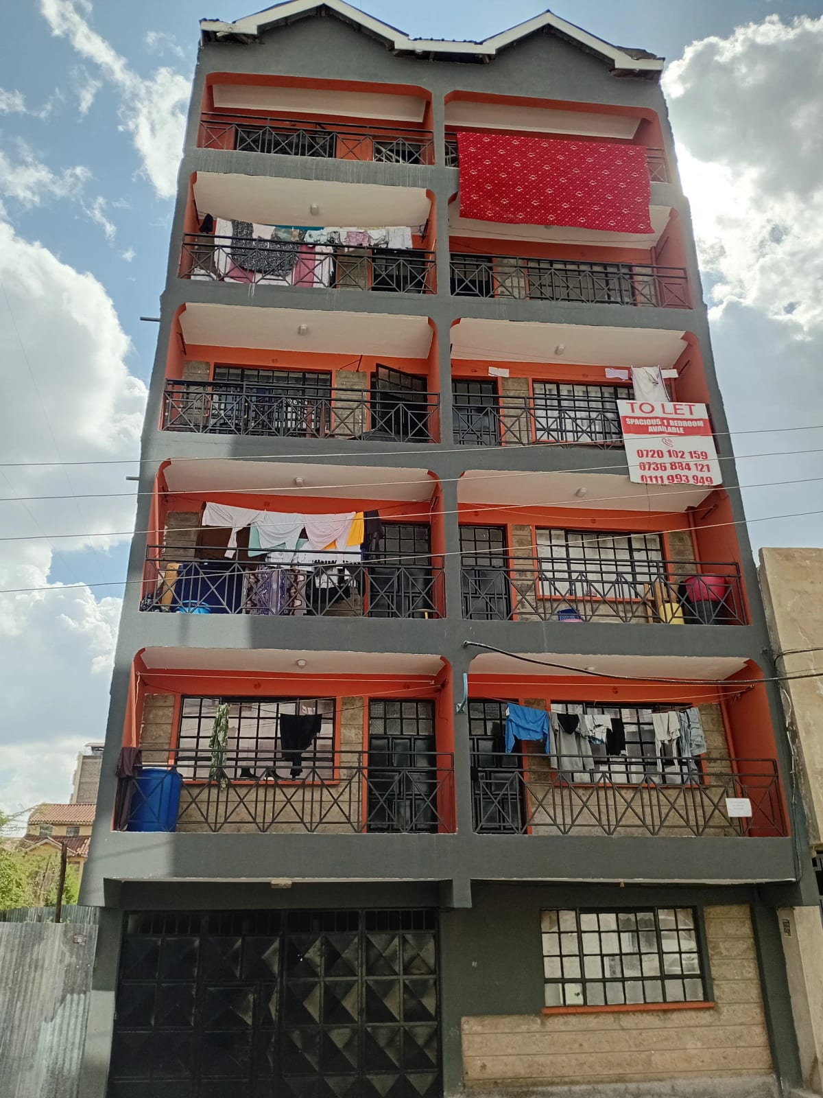 Multi-story residential building facade with red and orange trim