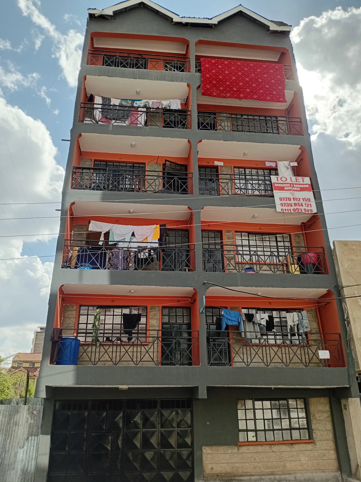 Multi-story residential building facade with red and orange trim