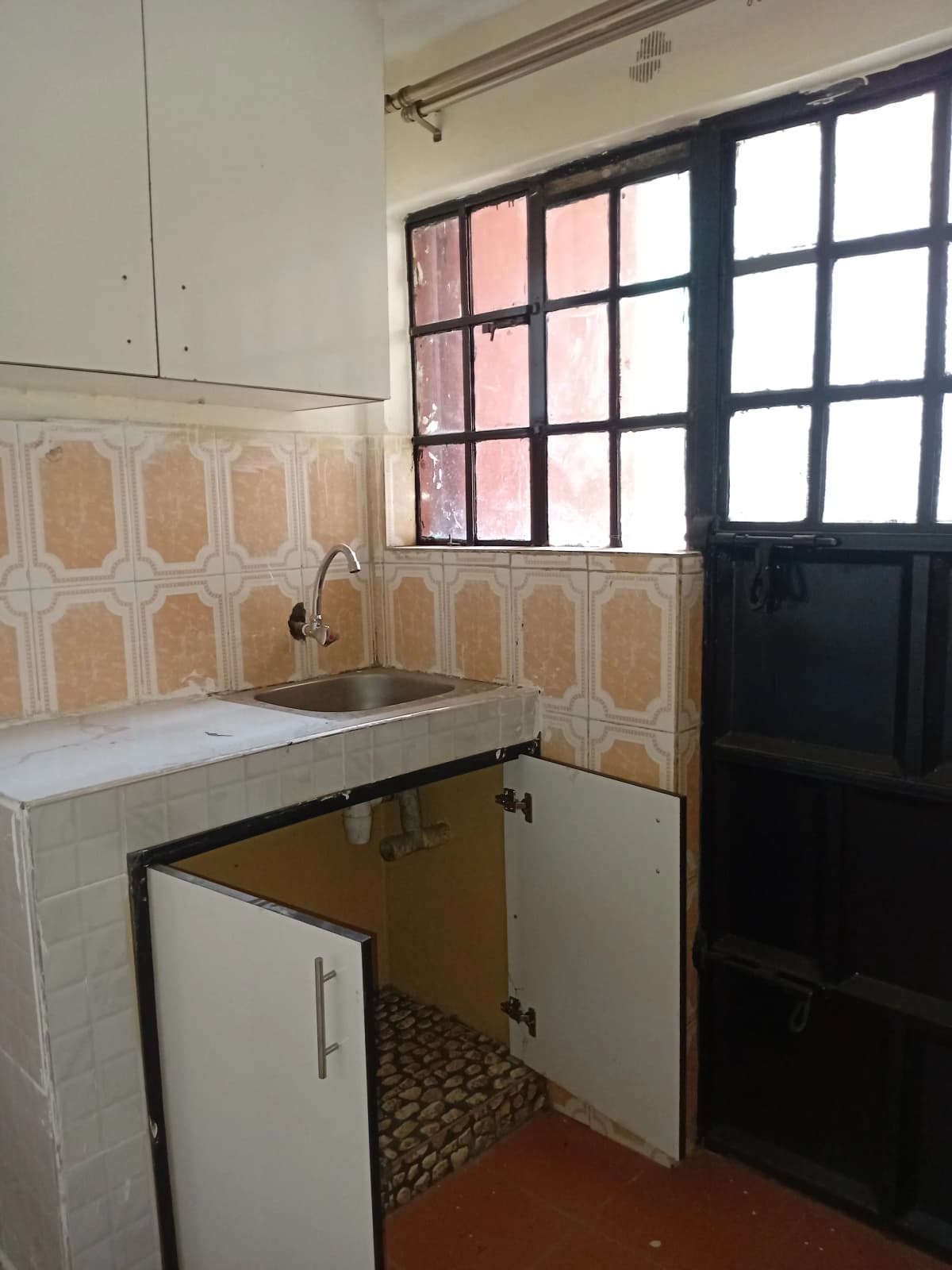 Compact kitchen with sink, storage cabinets, geometric tile backsplash