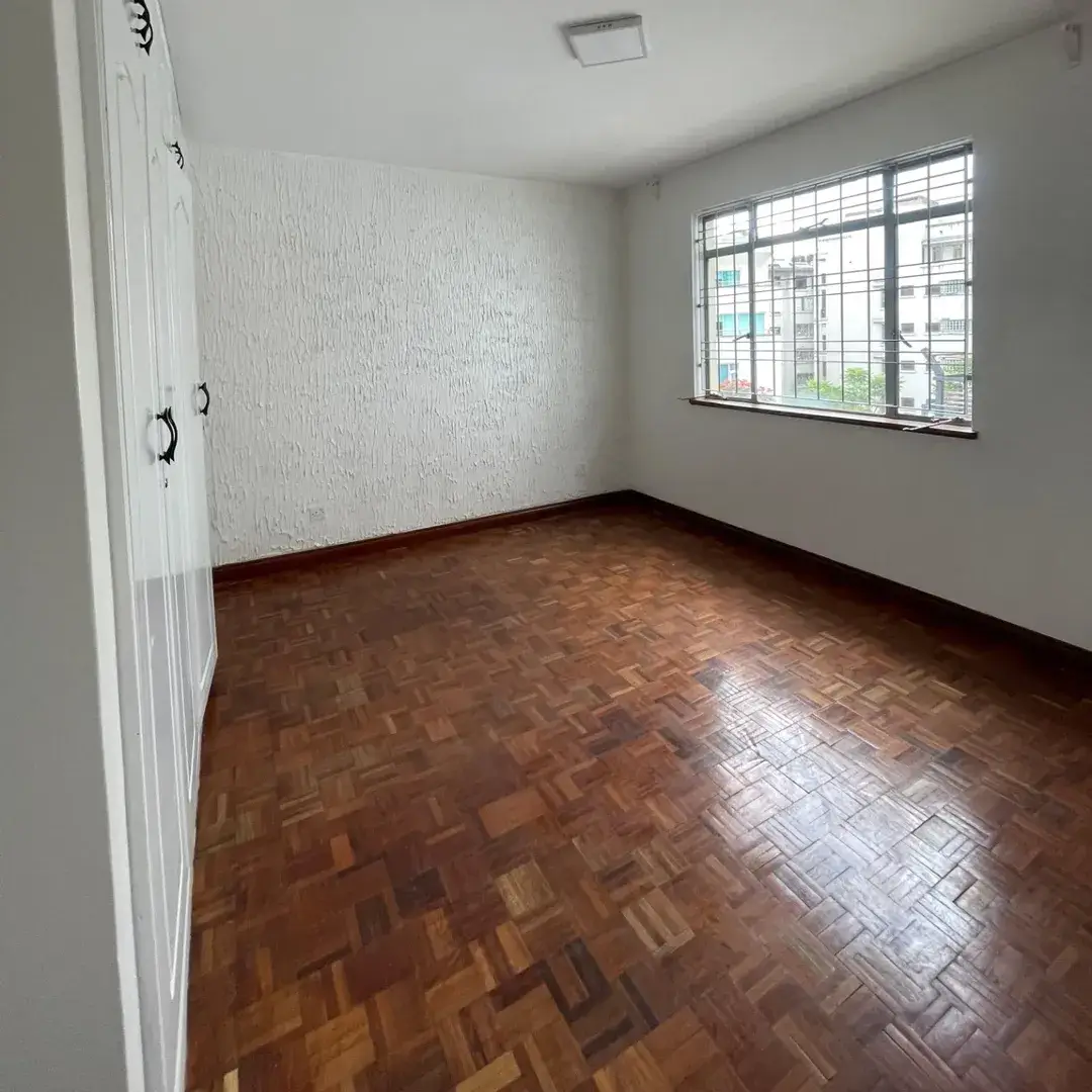 Empty bedroom with parquet flooring and large window