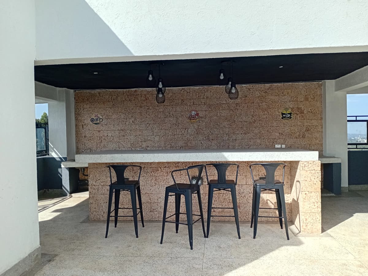 Open-plan rooftop kitchen with brick feature wall and bar seating