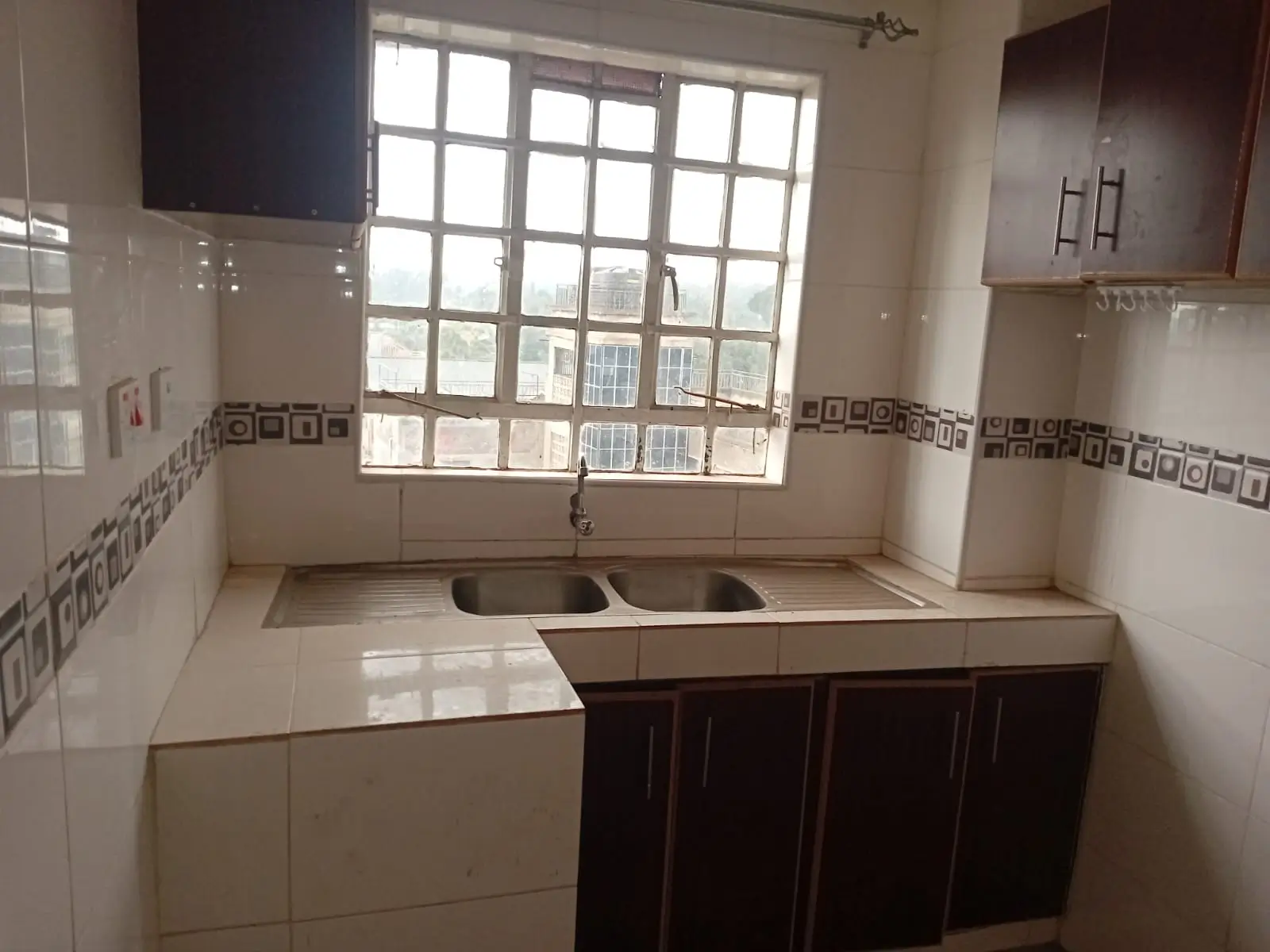 Compact kitchen with dual sink and dark cabinetry, bright windows
