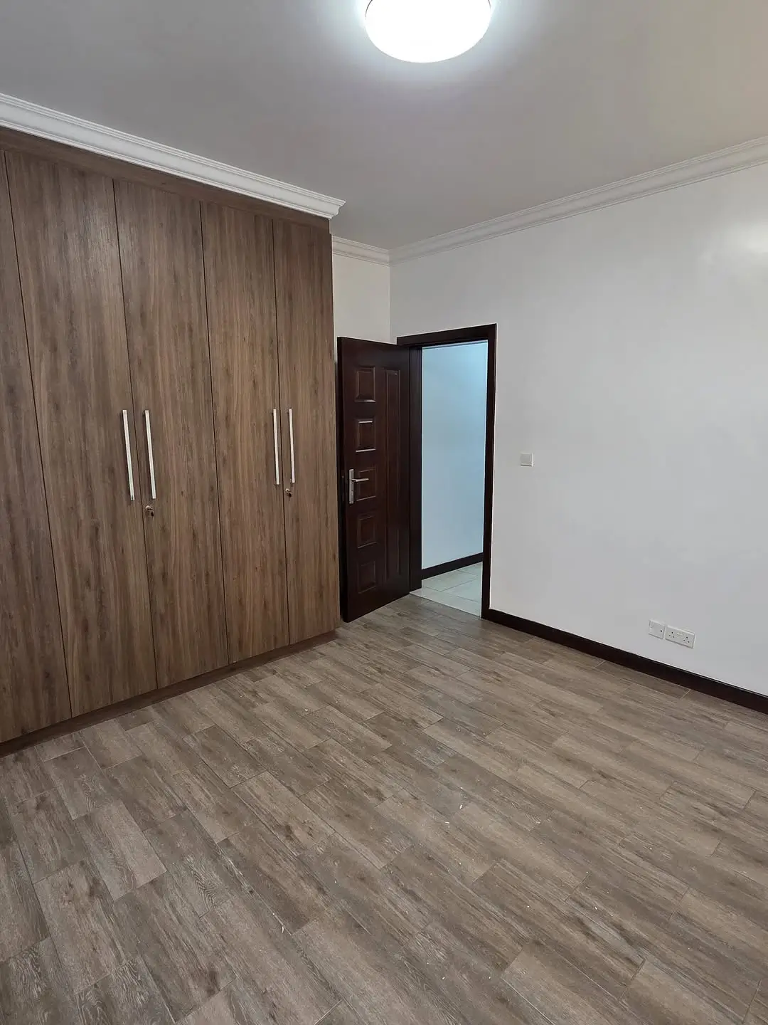 Spacious bedroom with wooden wardrobe and laminate flooring