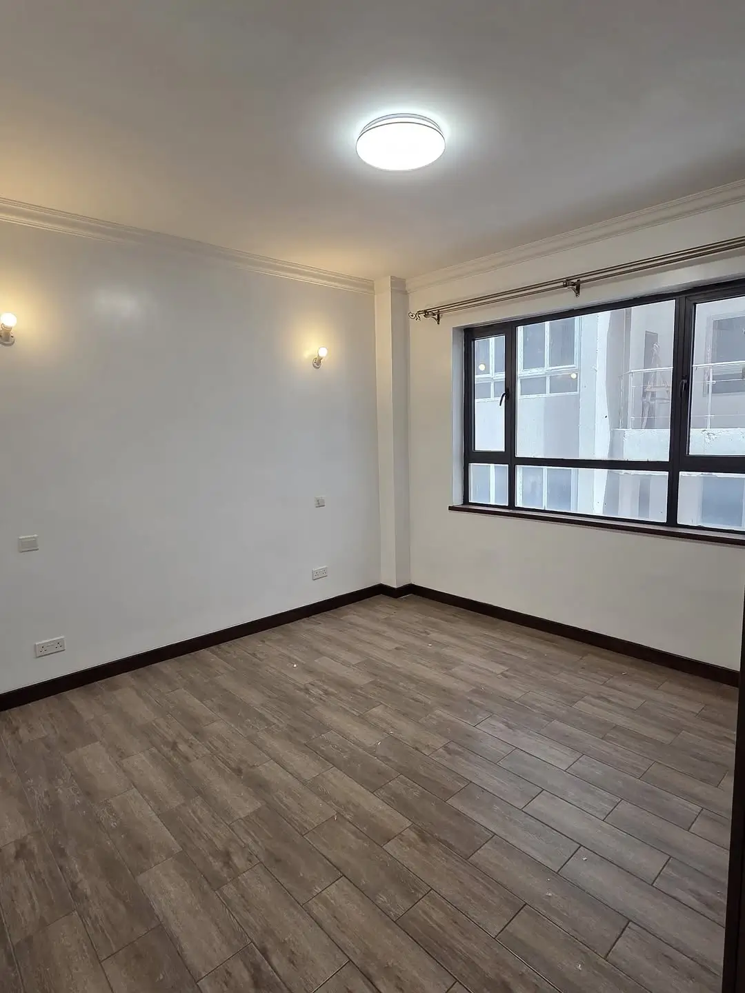 Spacious bedroom with wooden flooring and large windows
