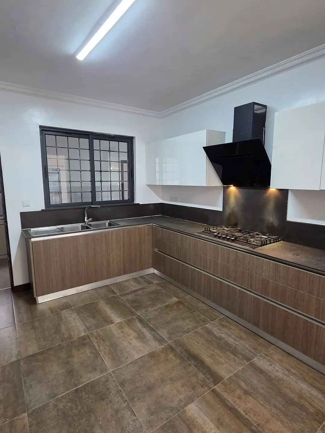Modern L-shaped kitchen with wood cabinetry and black cooktop