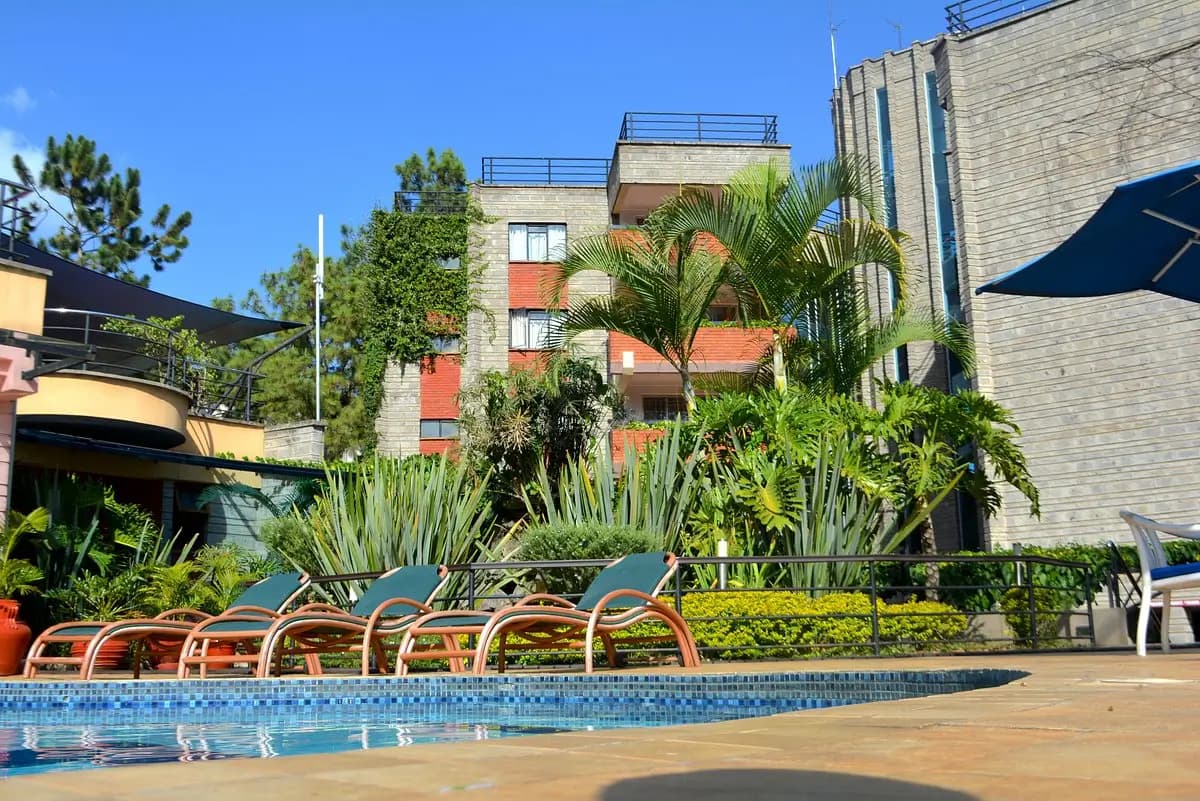 Resort-style pool with loungers, tropical plants, modern building