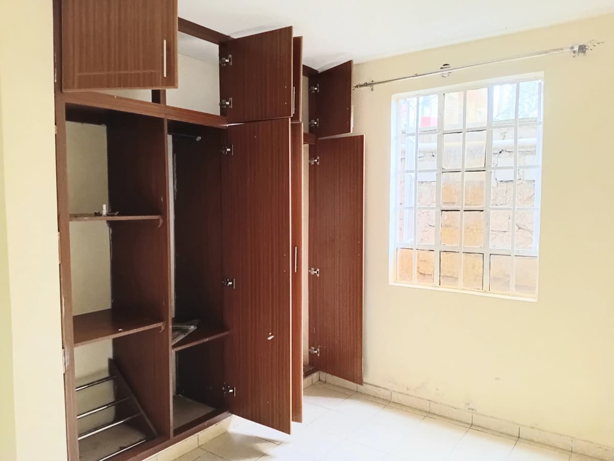 Bedroom with built-in wooden wardrobe and bright window