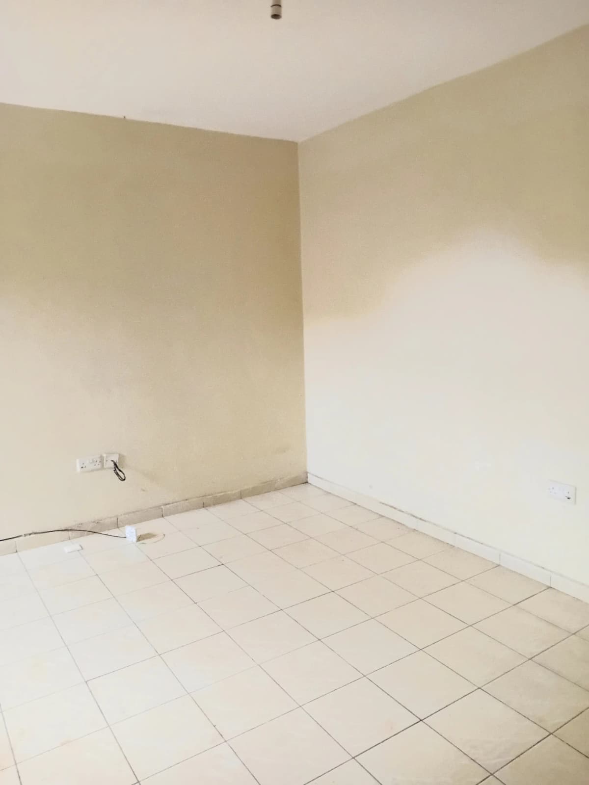 Empty kitchen space with cream walls and tiled flooring
