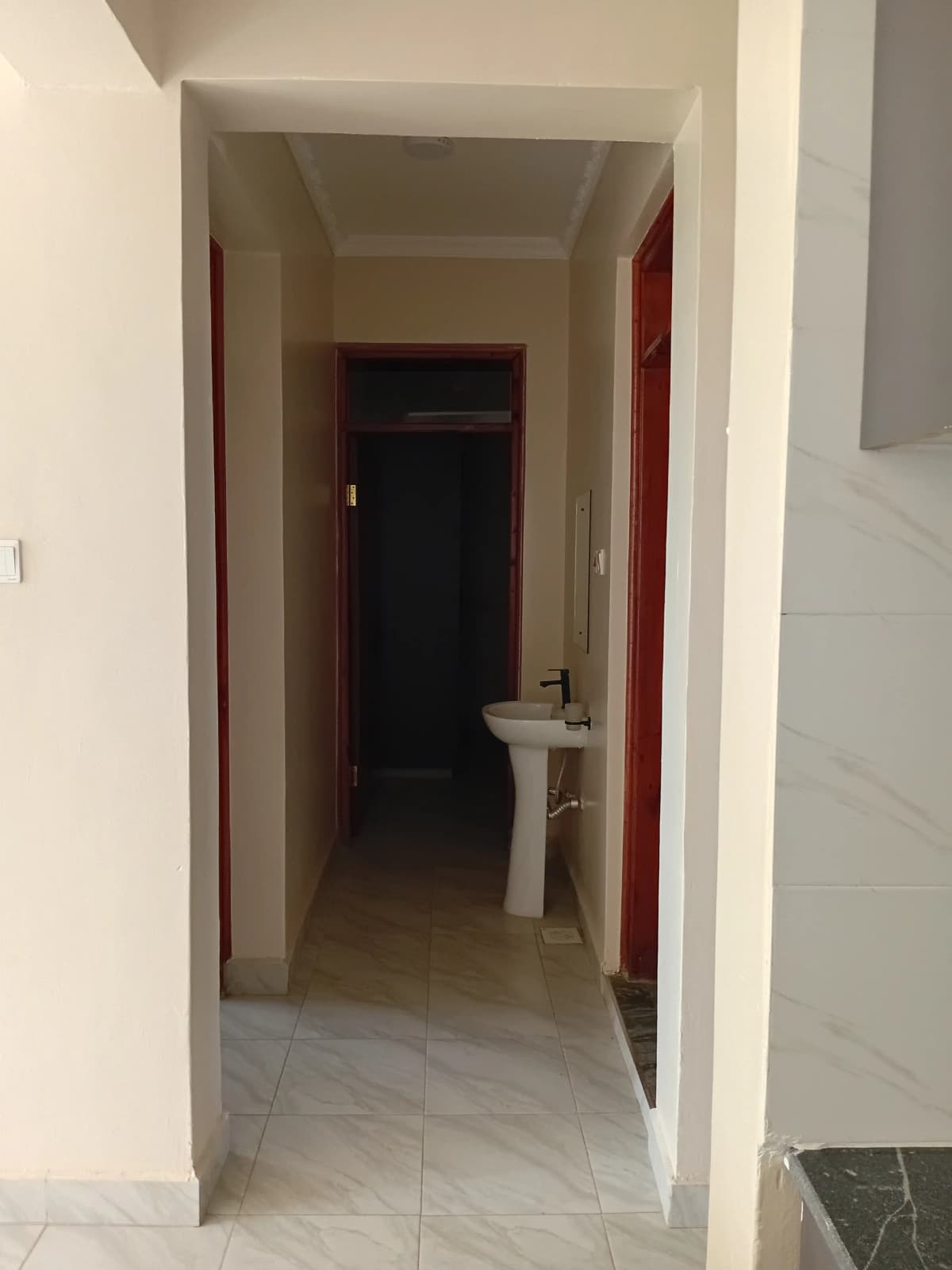 Narrow corridor with red-trimmed doors and tile flooring