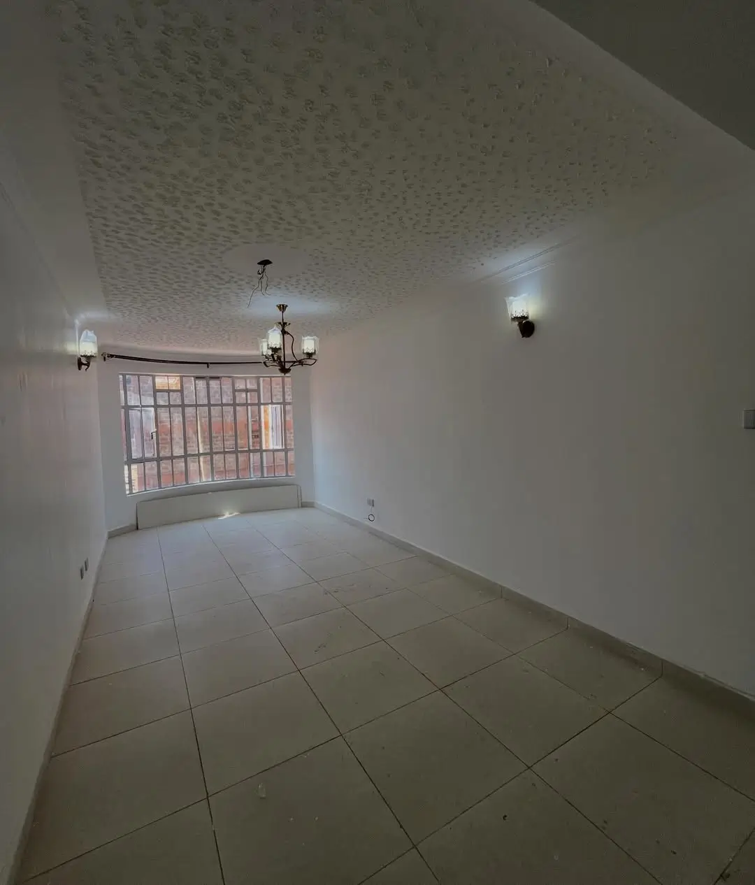 Empty living room with tiled floors and barred window