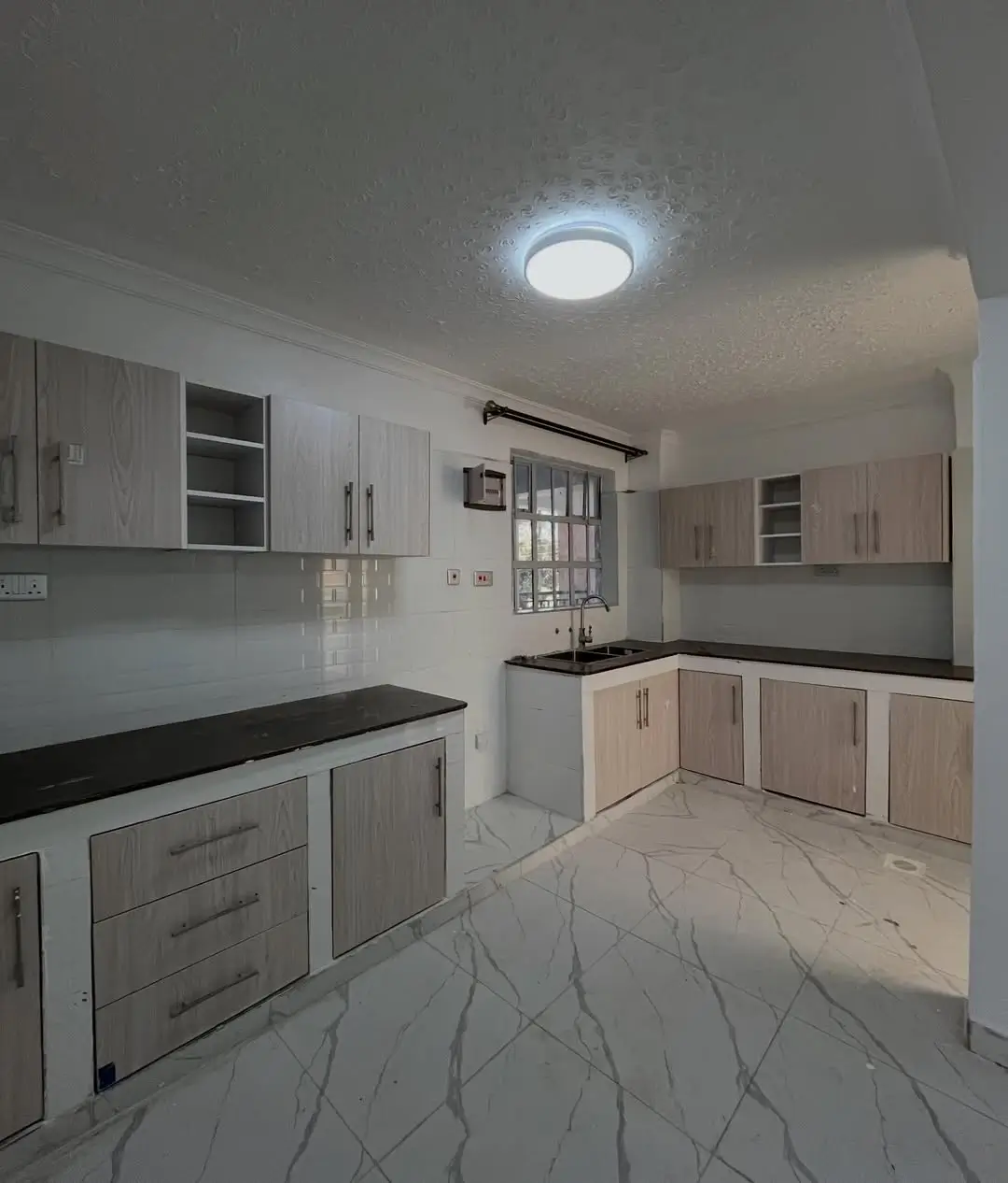 Modern kitchen with light cabinetry and black granite countertops