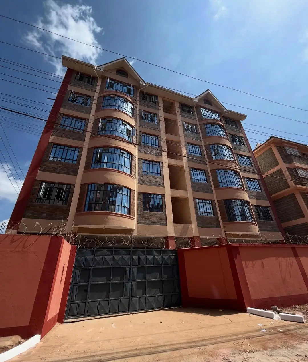 Multi-story residential building with red gate and compound