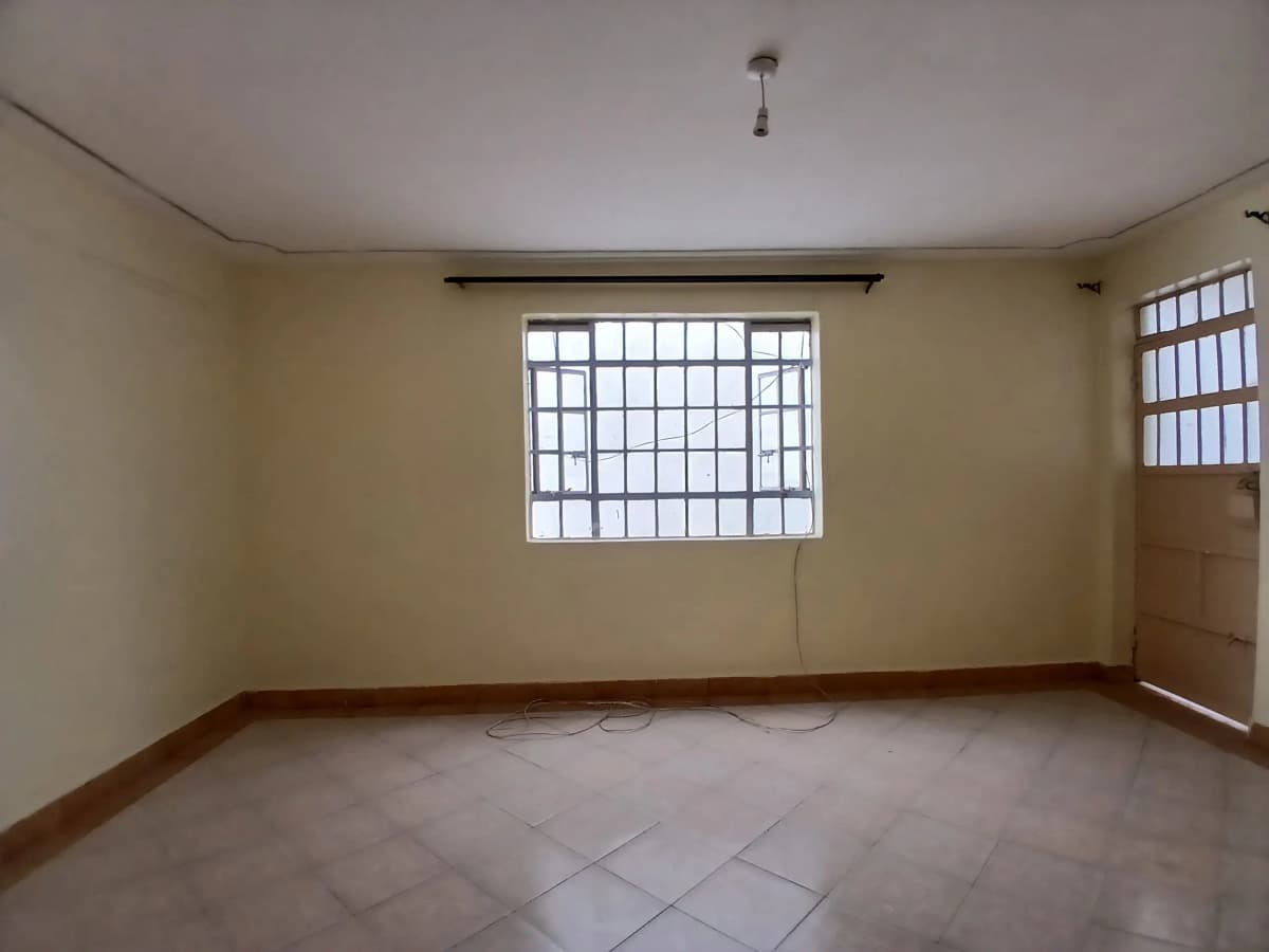 Spacious empty room with barred window and tiled floor