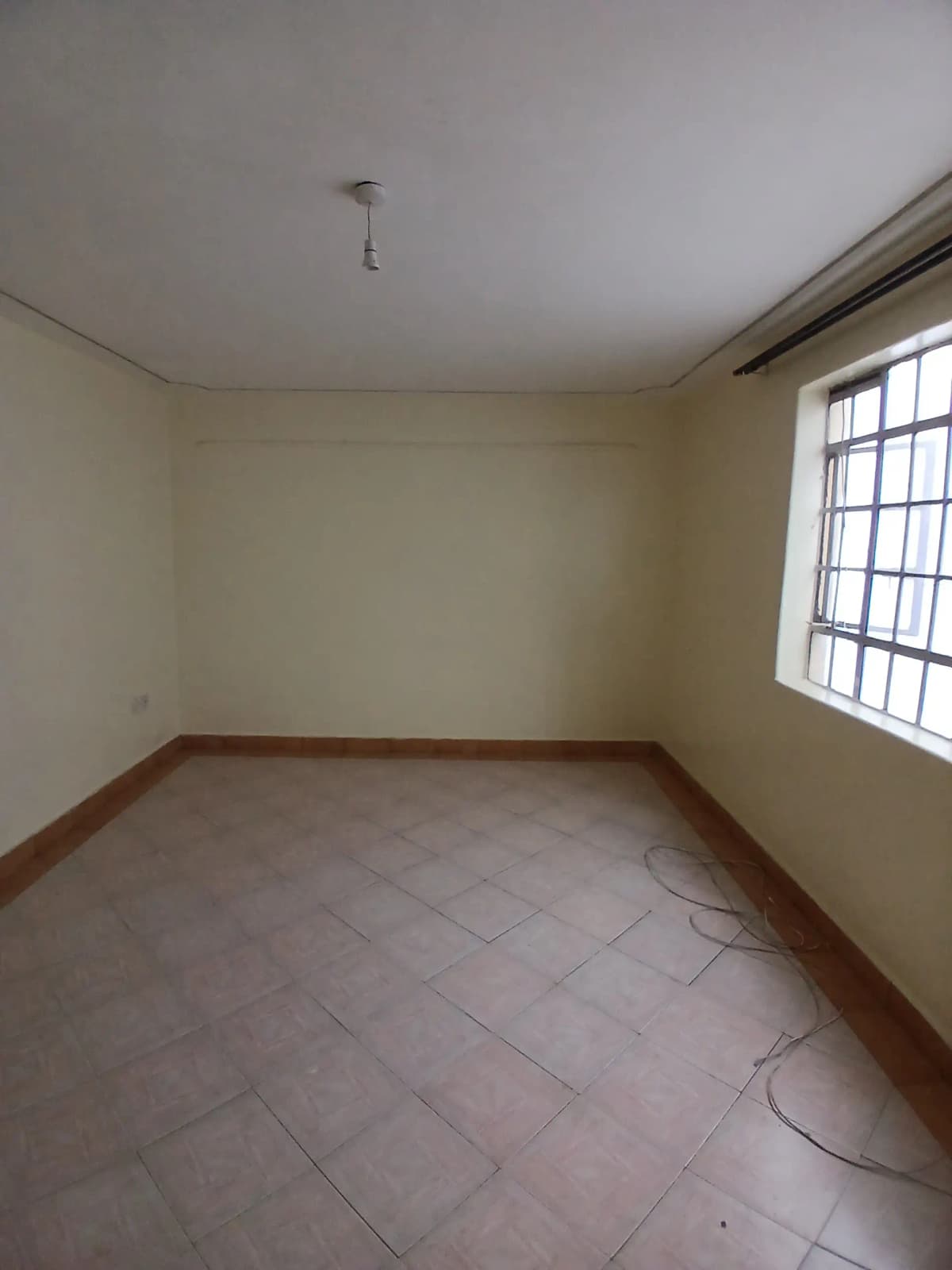 Empty bedroom with terracotta tile flooring and natural light