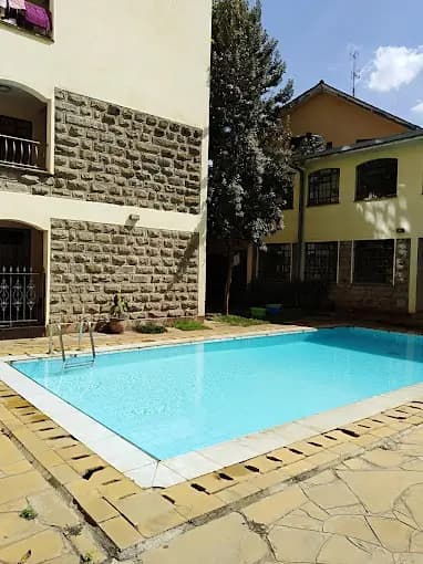 Rectangular swimming pool with paved deck and surrounding buildings