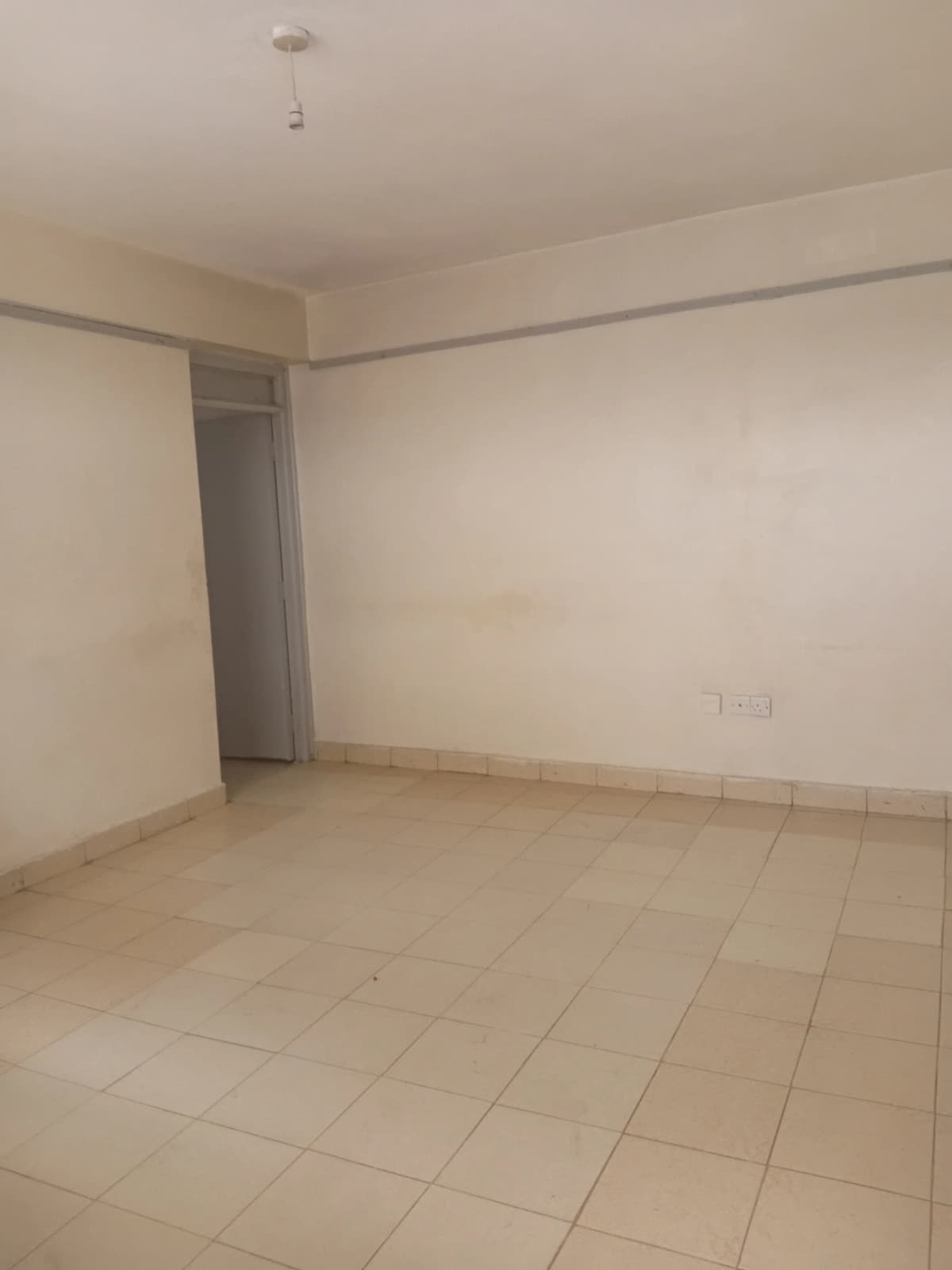 Empty living room with tiled floor and neutral walls