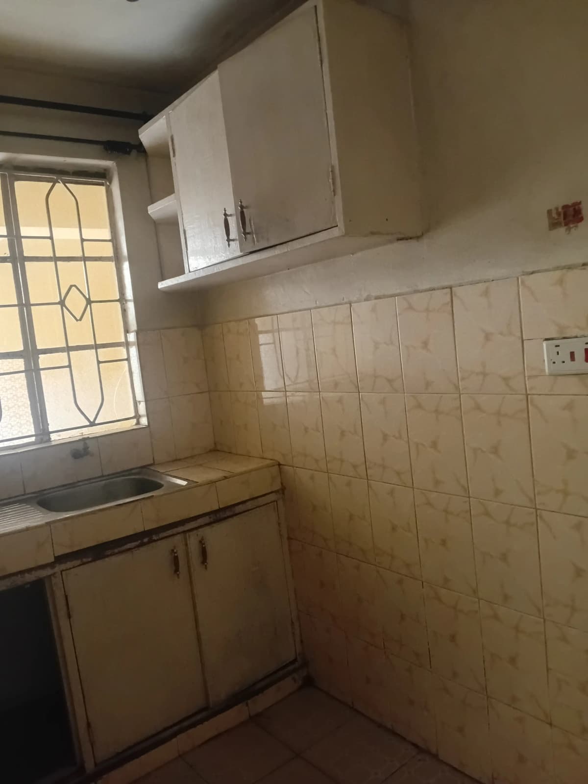 Compact kitchen with cream cabinetry and window for natural light