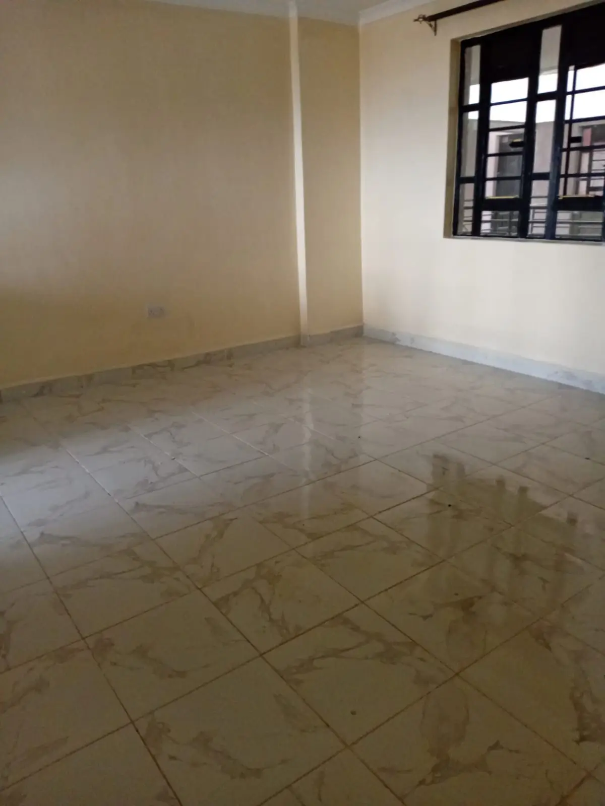 Empty bedroom with tiled floor and barred window