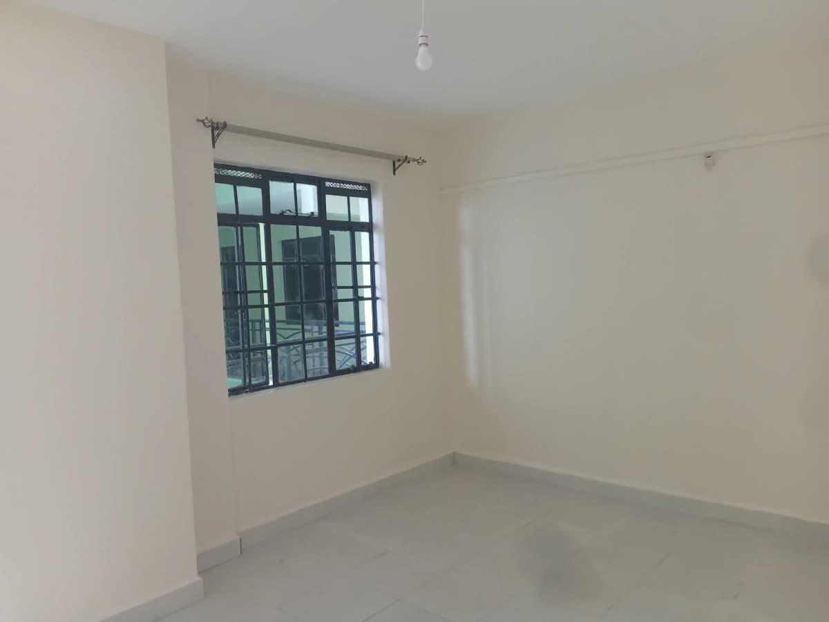 Empty bedroom with barred window and concrete floor