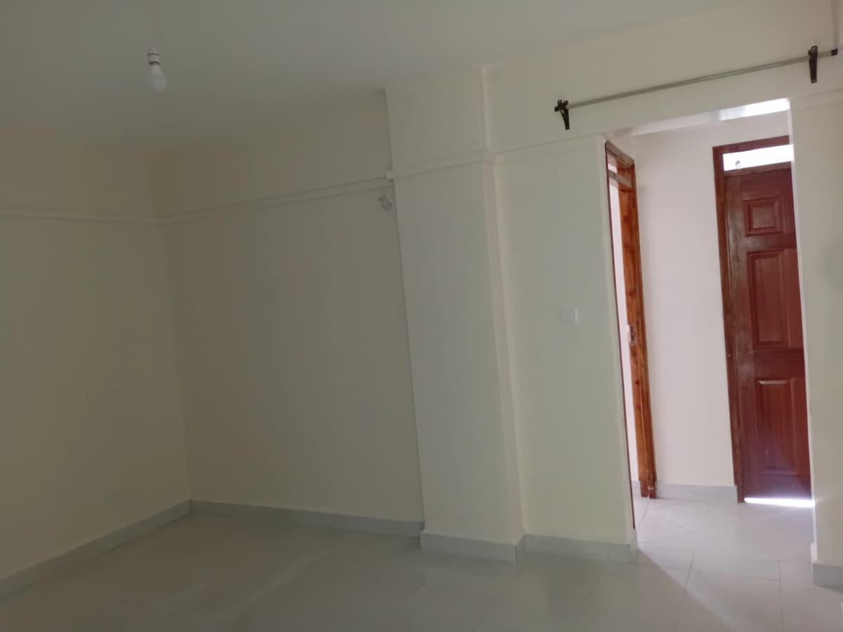Empty living room with white walls and red door entry