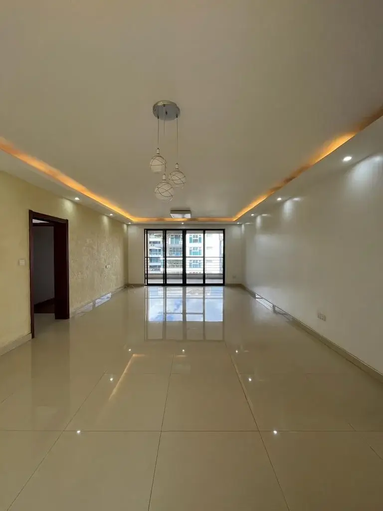 Spacious empty living room with ambient ceiling lights and balcony view