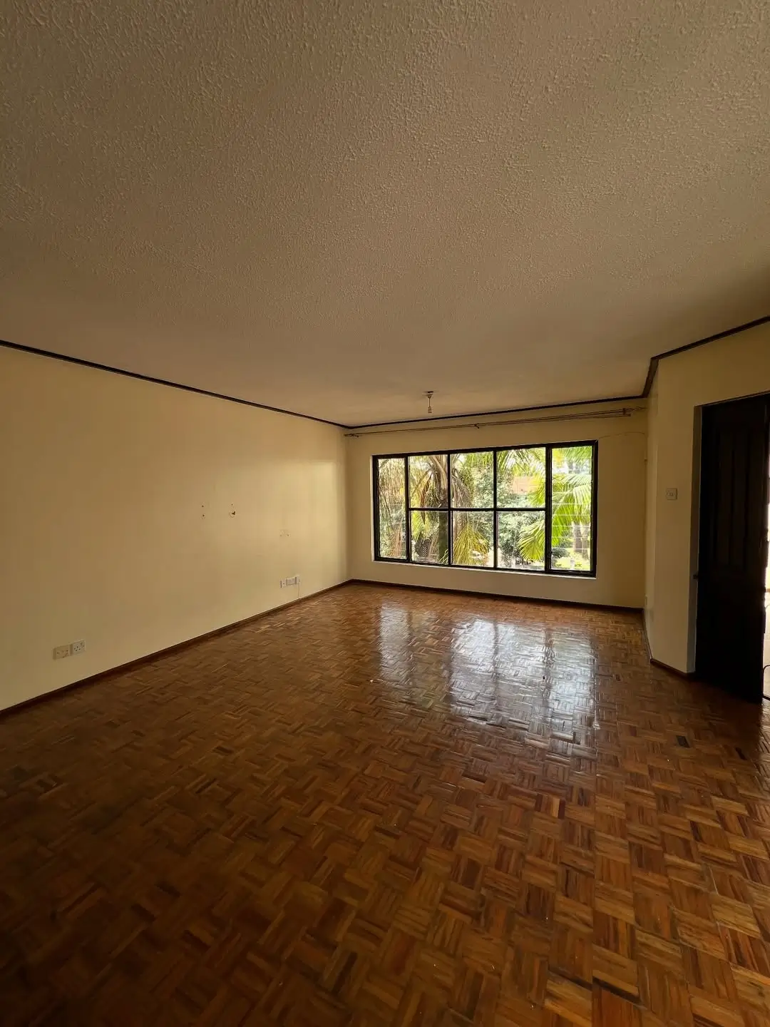 Spacious living room with herringbone floor and garden views
