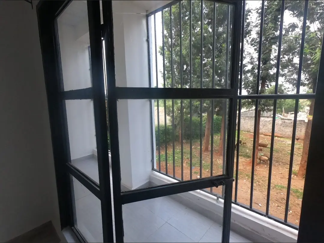 Enclosed balcony with black iron railings overlooking green landscape