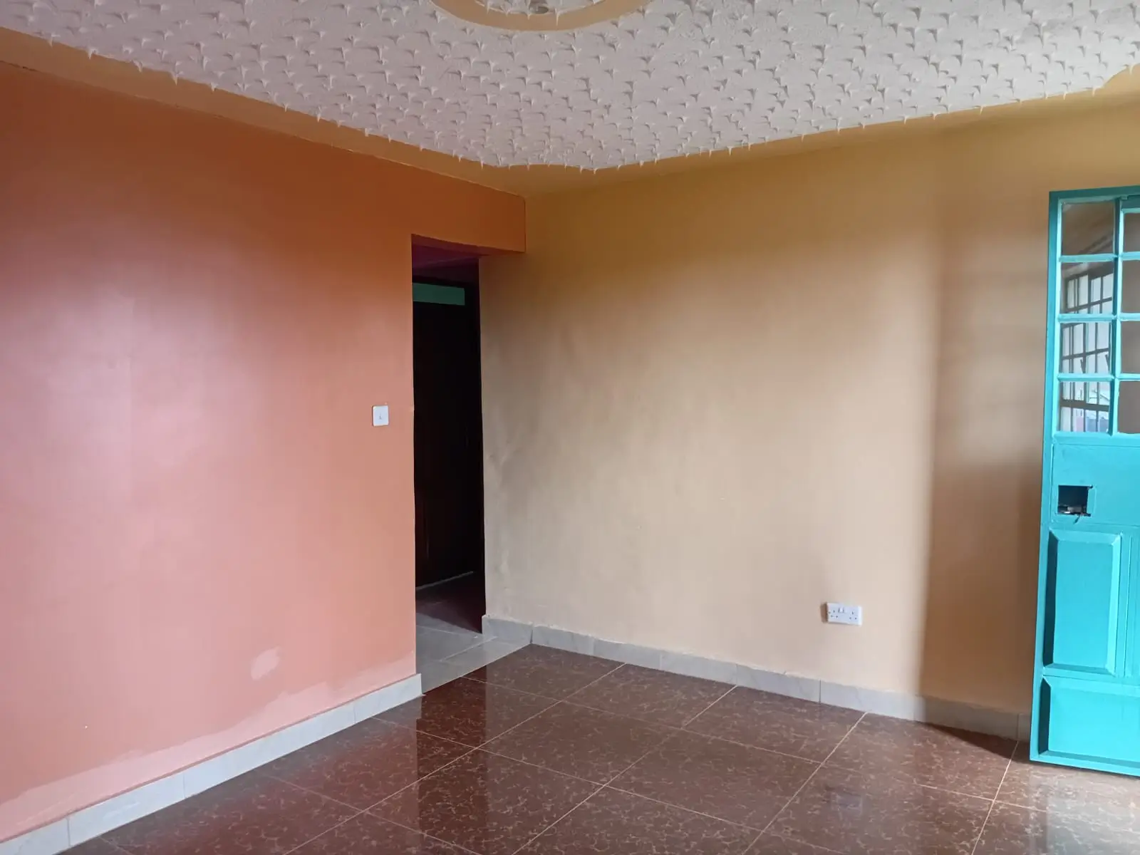 Empty living room with pink and cream walls, tiled floor
