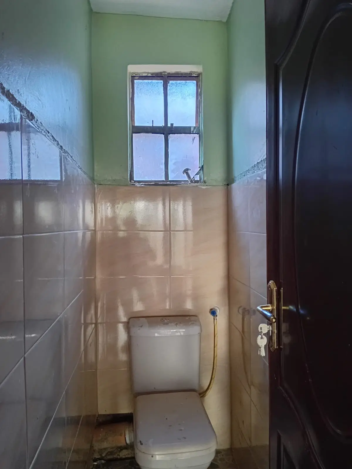 Small toilet room with cream tile walls and window