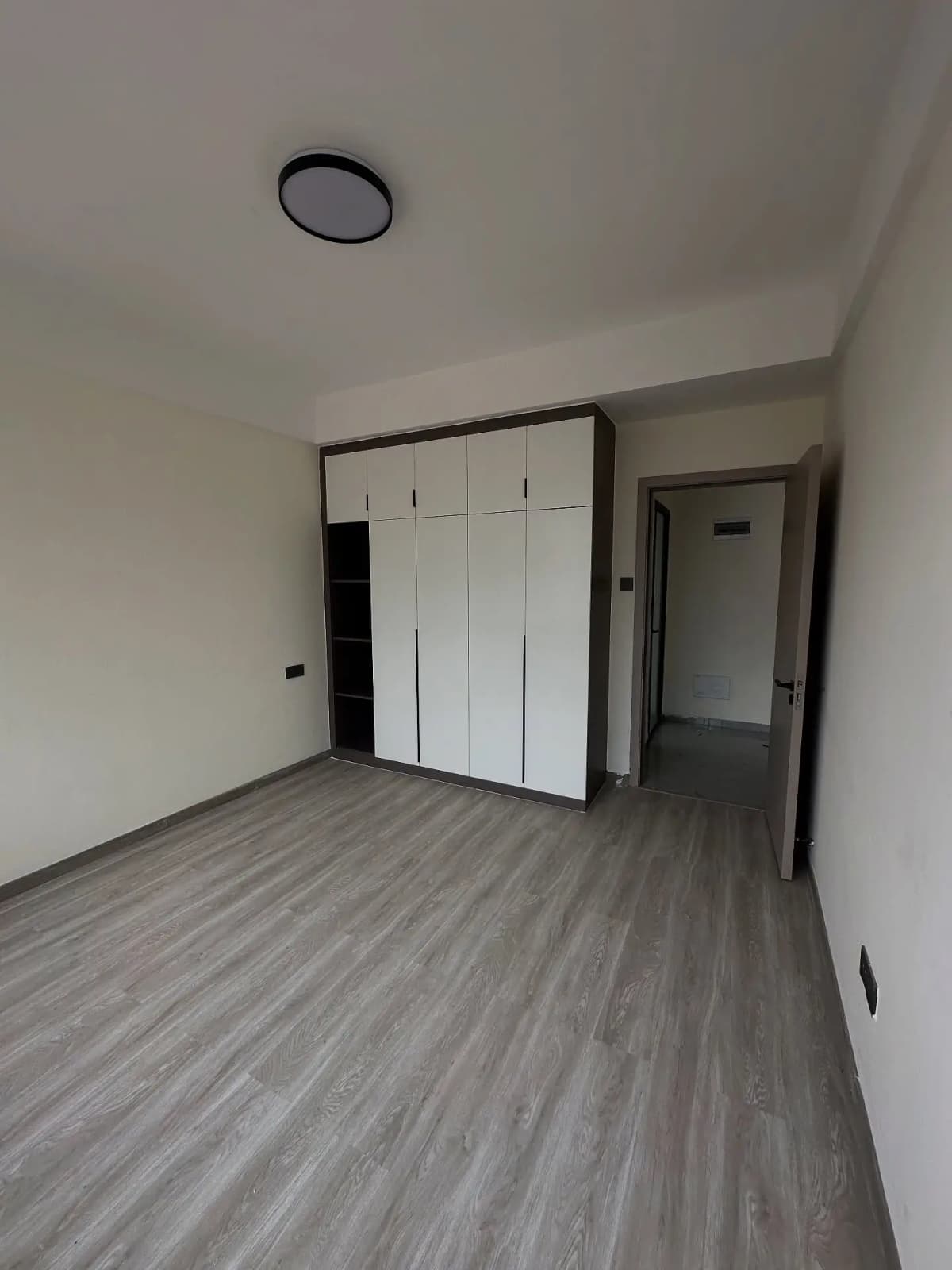 Empty bedroom with built-in wardrobes and wooden flooring