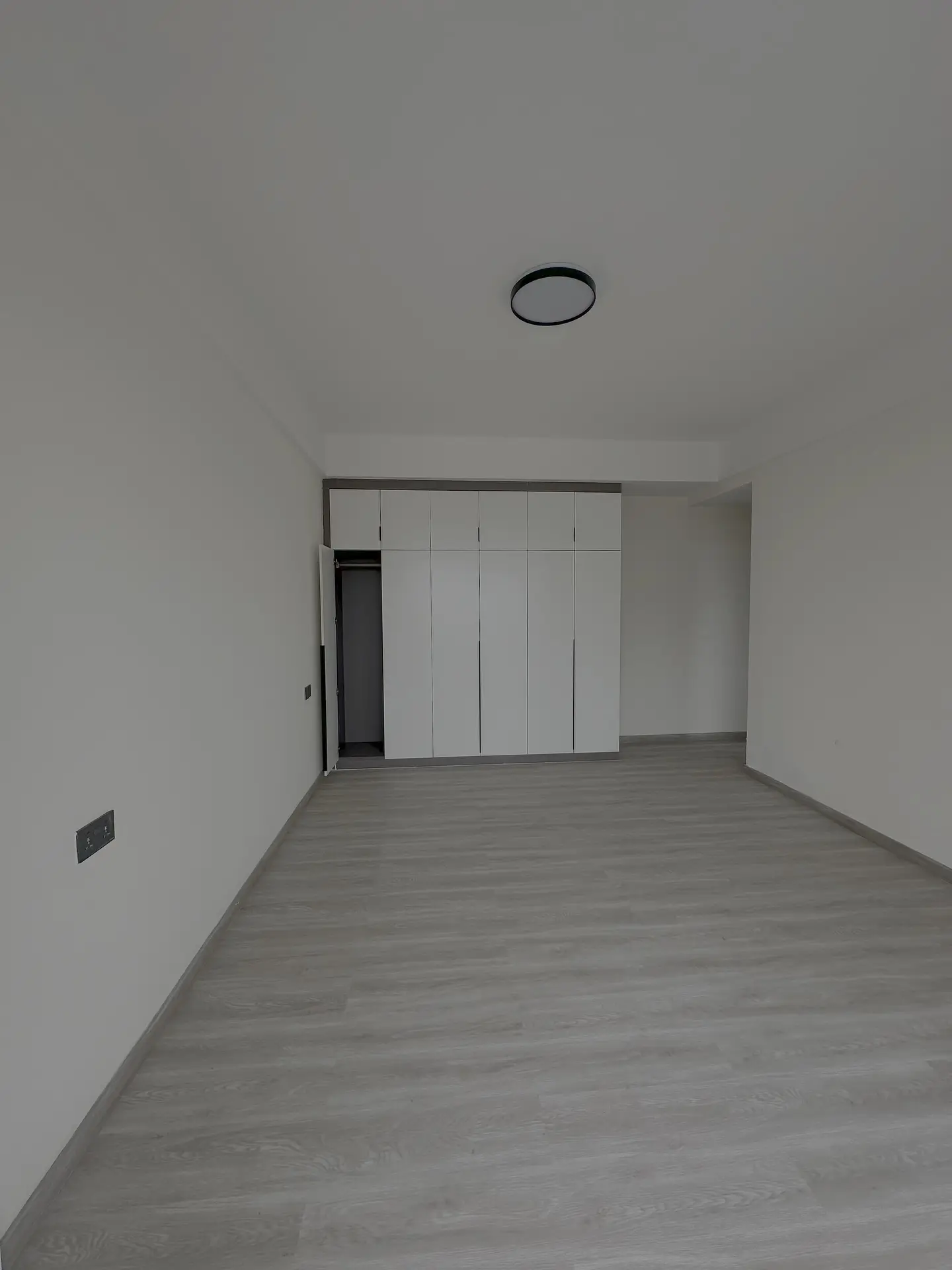 Empty bedroom with built-in wardrobes and wooden flooring
