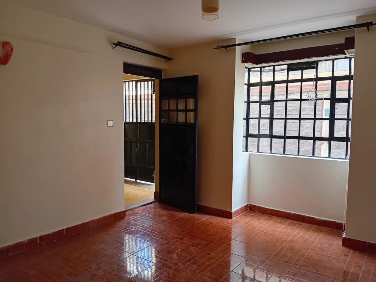 Spacious living room with polished red tile floor and natural light