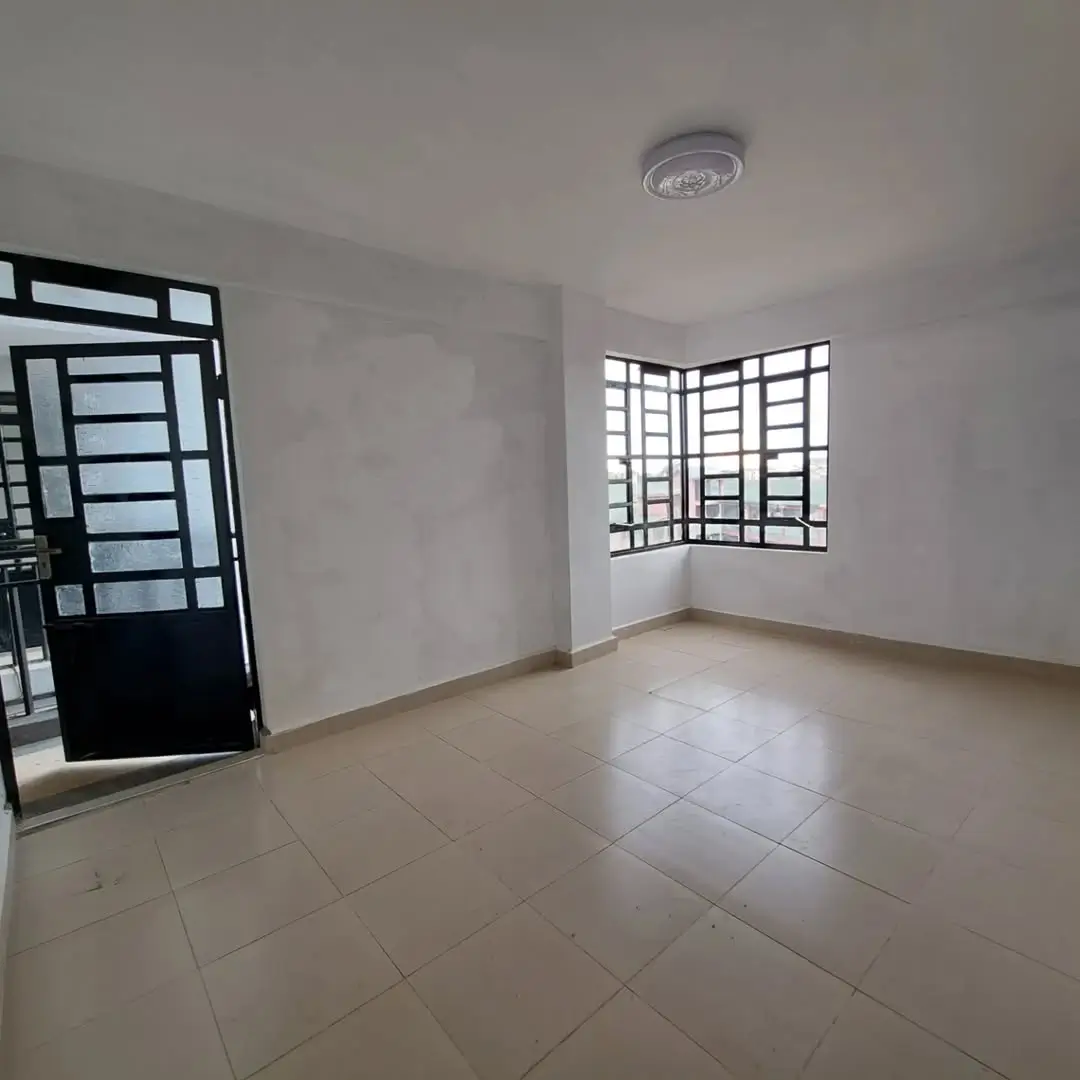 Spacious empty living room with tiled flooring and natural light