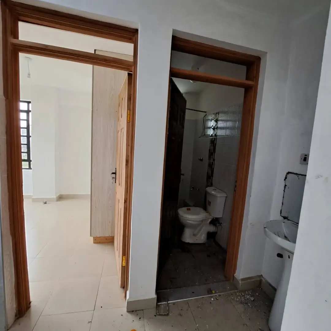 Compact bathroom with toilet and basin visible through doorway