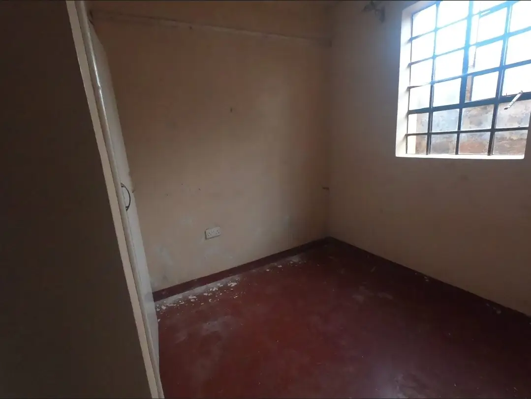 Unfurnished bedroom with high window and red tile flooring