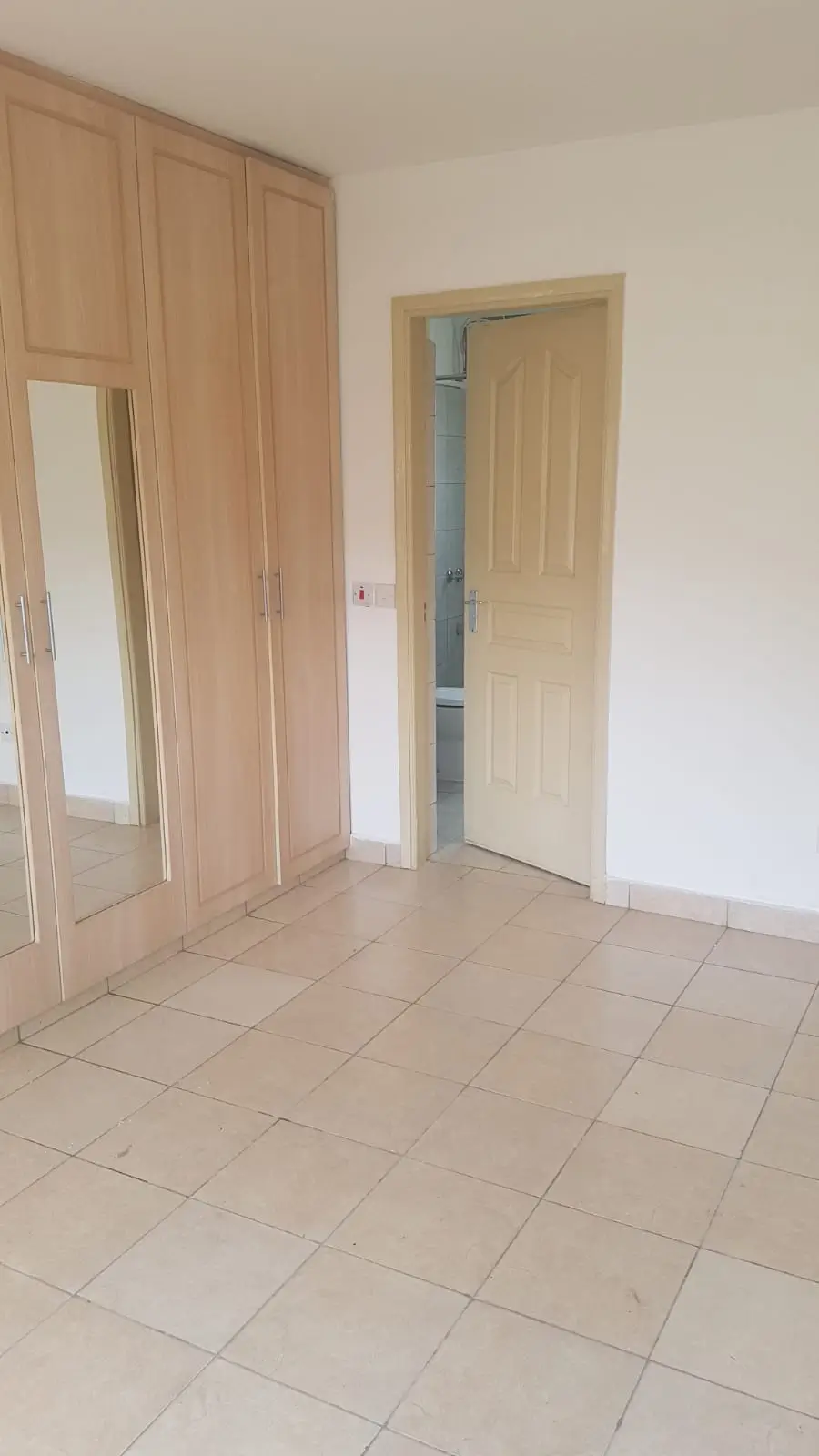 Spacious bedroom with built-in wardrobe and tiled flooring