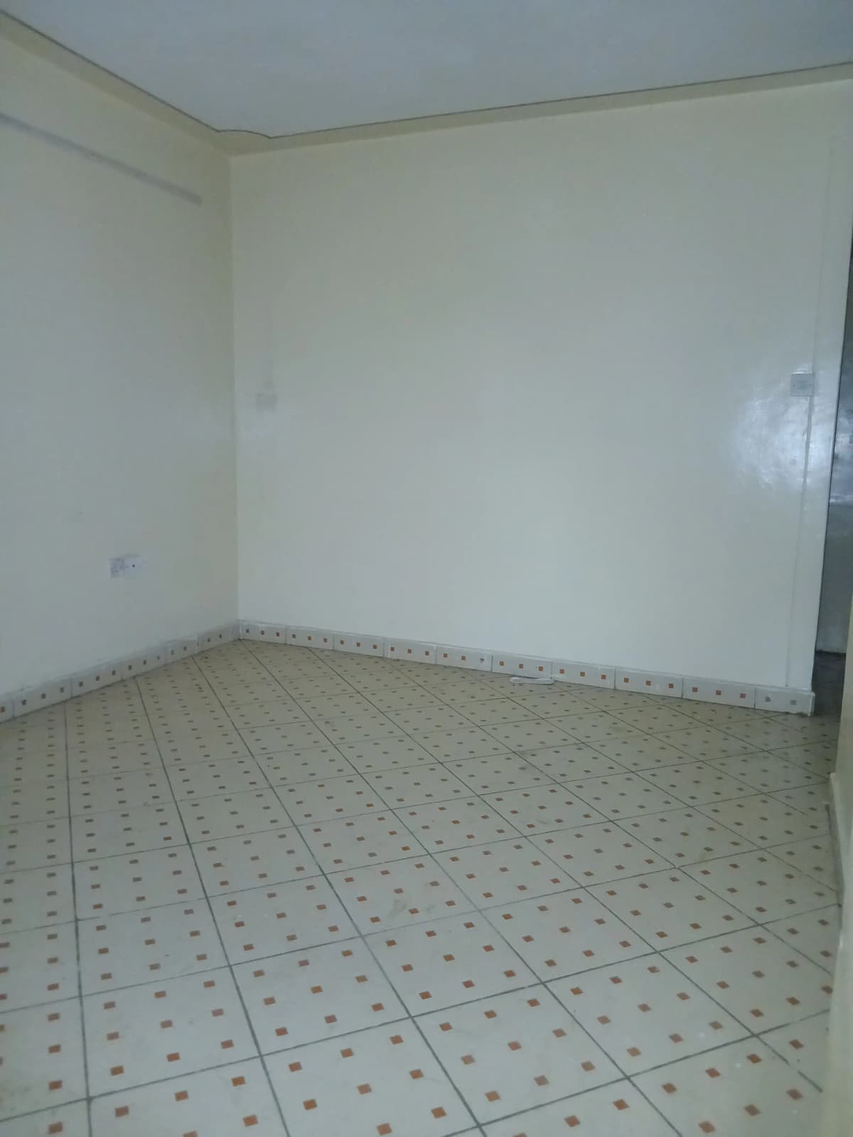Empty room with patterned tile flooring and plain walls
