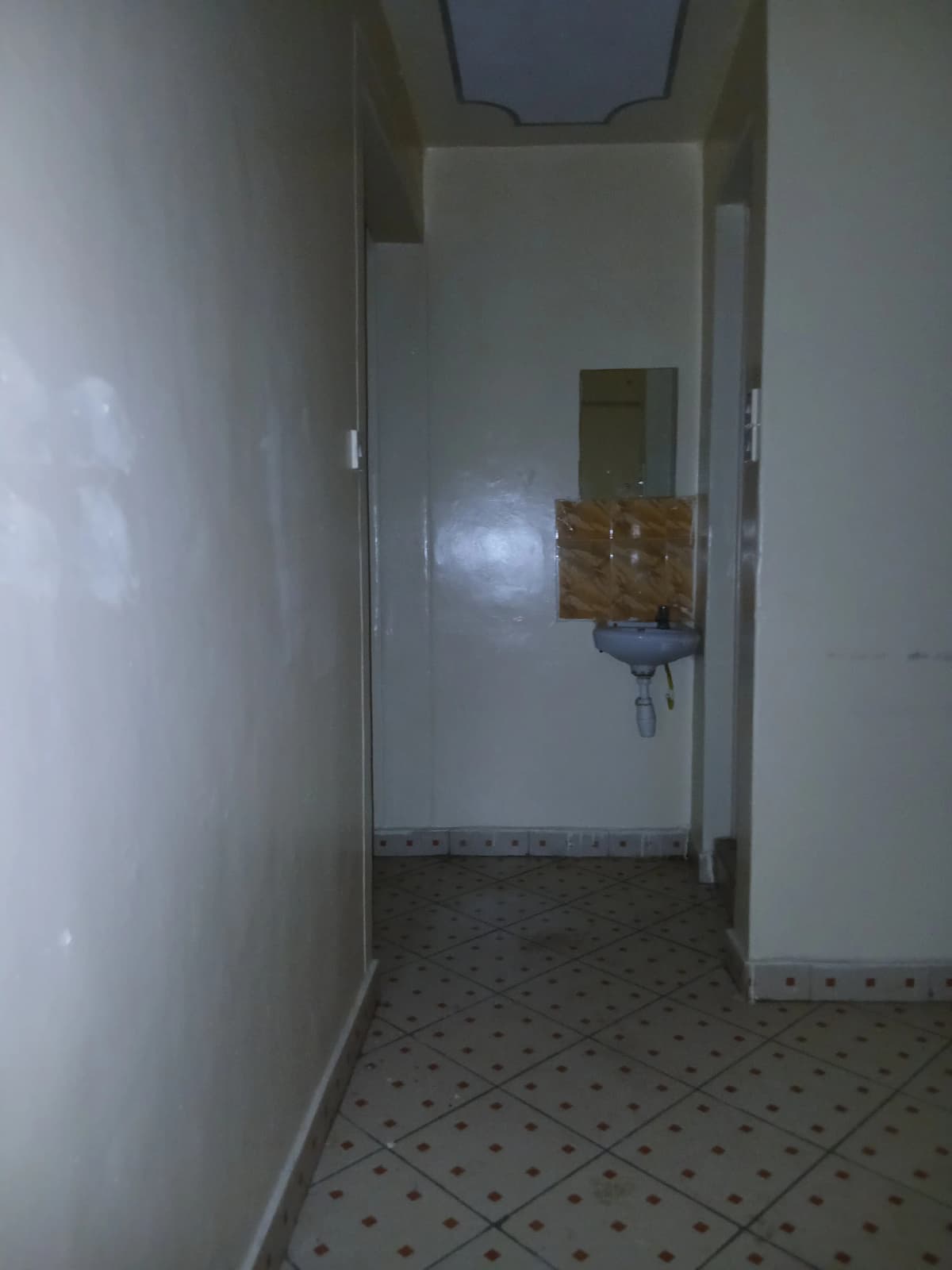 Narrow corridor with tiled floor and neutral walls