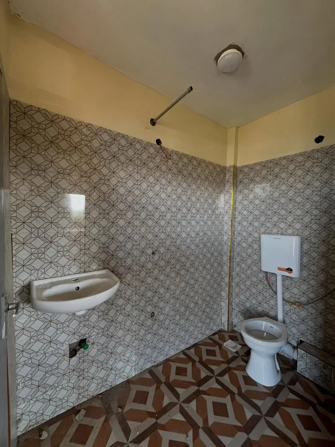 Bathroom with geometric tile walls, sink, toilet, shower enclosure