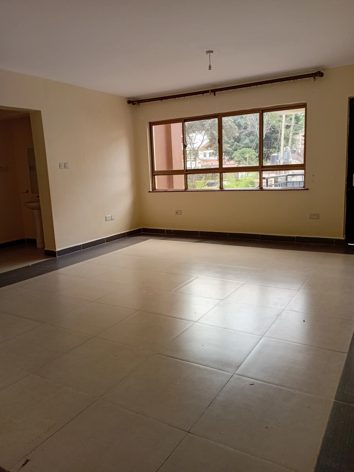 Spacious living room with large windows and polished tile flooring