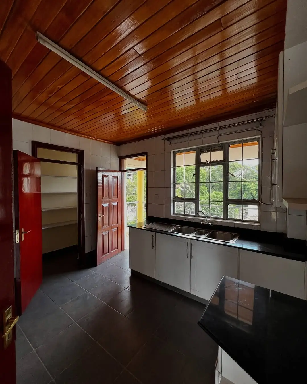Modern kitchen with black countertops, wooden ceiling, natural light