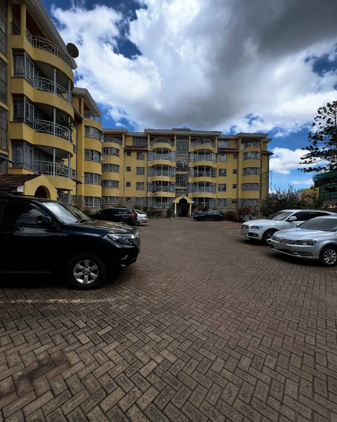 Multi-story residential building with paved parking lot and vehicles