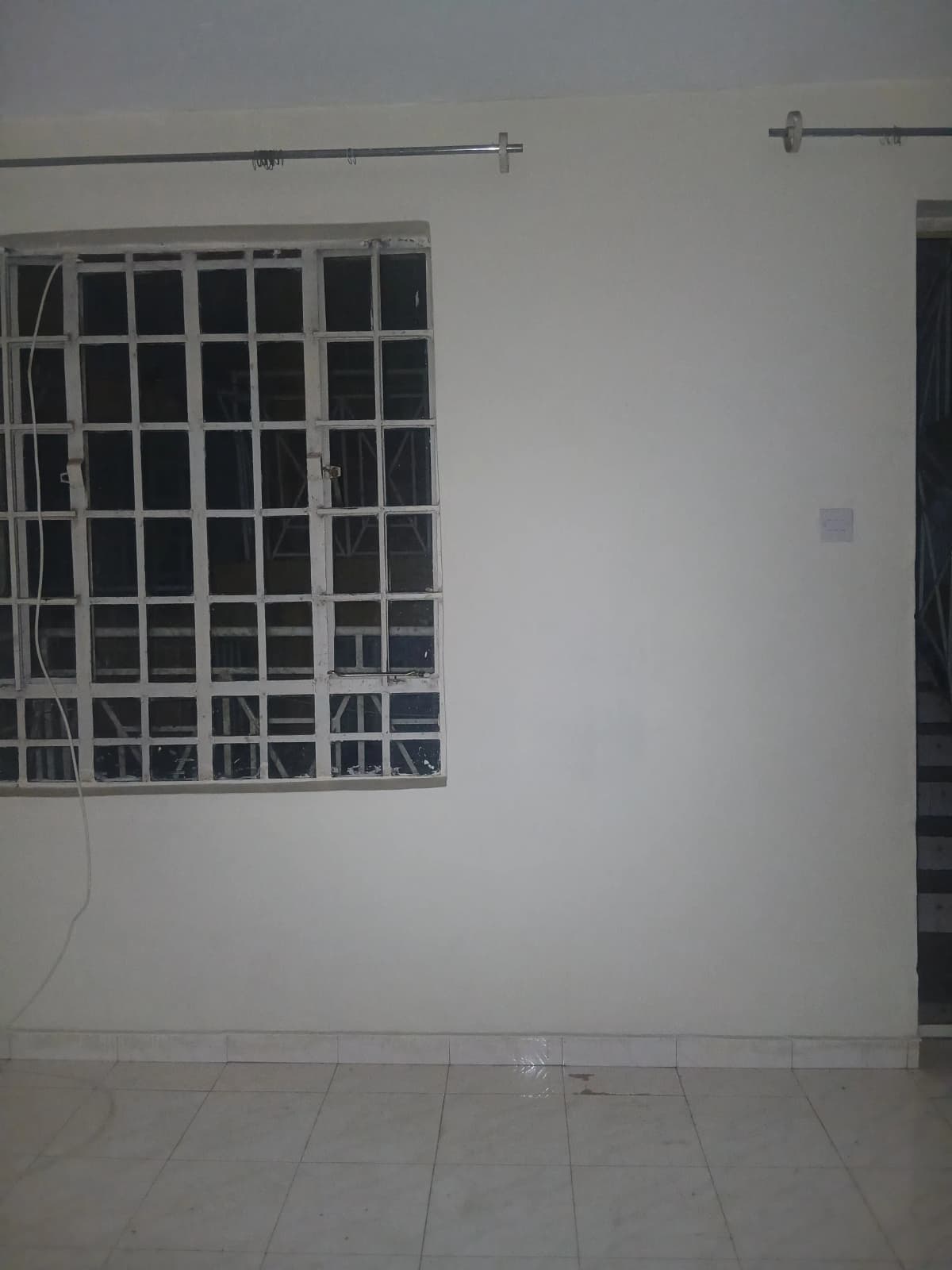 Empty bedroom with barred window and minimal furnishings