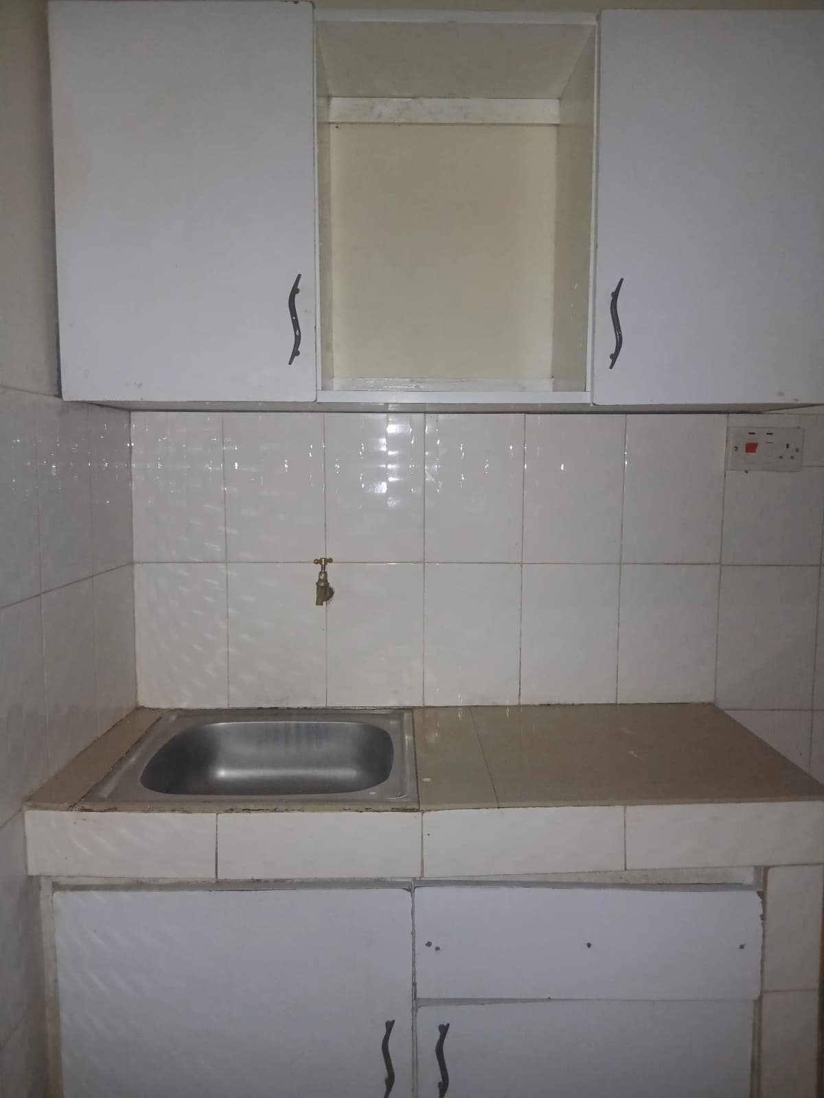 Compact kitchen with white tile backsplash and stainless steel sink